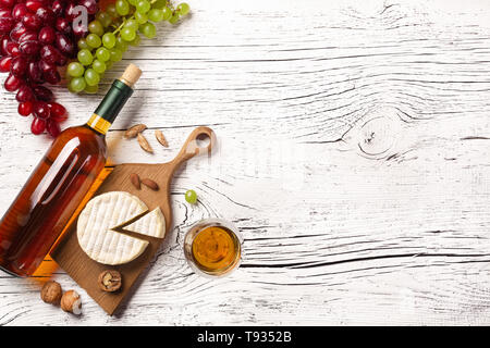 Weiße Flasche Wein, Trauben, Käse und Weinglas auf weißem Holzbrett. Ansicht von oben mit der Kopie. Stockfoto