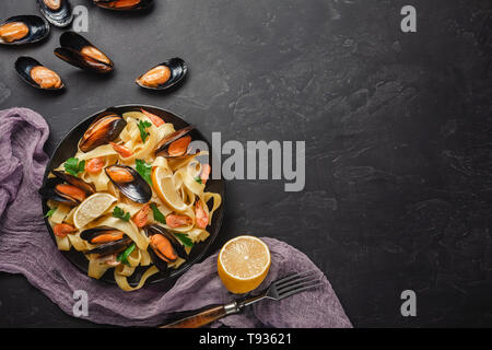 Spaghetti Vongole, Italienisch, Meeresfrüchte, Nudeln mit Muscheln und Miesmuscheln, in der Platte mit Kräutern auf rustikalem Stein Hintergrund. Traditionelle italienische Meer Küche, Clos Stockfoto