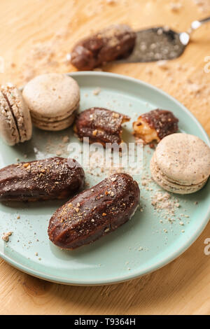 Mit köstlichen Eclairs und macarons auf hölzernen Tischplatte, Nahaufnahme Stockfoto