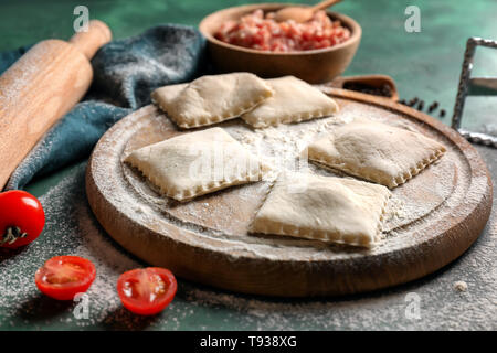 Holzbrett mit rohen Ravioli auf Tisch Stockfoto