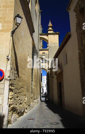 Typische schmale Gasse mit Bögen kontrastieren mit dunkelblauen Himmel im traditionellen Dorf Arcos de la Frontera in der Provinz Andalusien, Spanien Stockfoto