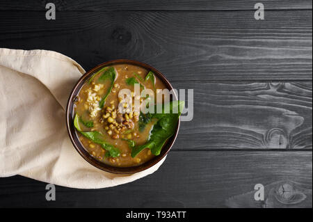 Mung dhal mit grünen Spinat am schwarzen Holz der Tischplatte. Moong Dal - Indische Küche Curry. Vegetarisches Gericht mit zira und Koriander. Nach oben Ansichtskopie Raum Stockfoto