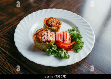 Runde Zucchini gefüllt mit Gemüse und Reis auf weiße Platte Stockfoto