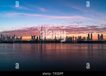 Morgen oder Sonnenaufgang, Dämmerung in Dubai. Schöne farbige wolkiger Himmel über der Innenstadt von Dubai. Lichtschein über Wolkenkratzer. Stockfoto