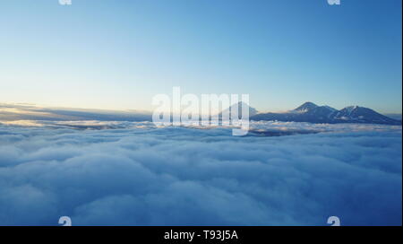 Sonnenuntergang Foto von Kamtschatka Vulkane. Hohe Höhe über Wolken. Schatten über Wolkenschicht und Berge Stockfoto