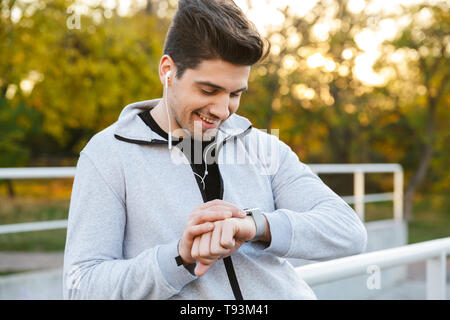 Lächelnd gesunde Sportler stehen im Freien am Geländer, smart Watch Stockfoto