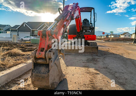Nahaufnahme von einem roten Bagger mit einem angehängt ist graderblatt an einem sonnigen Tag gesehen Stockfoto
