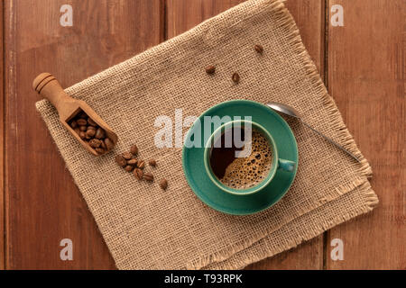 Eine Tasse schwarzer Kaffee mit gerösteten Kaffeebohnen, Schuß von oben auf einen dunklen Holzmöbeln im Landhausstil Hintergrund mit einem Platz für Text Stockfoto