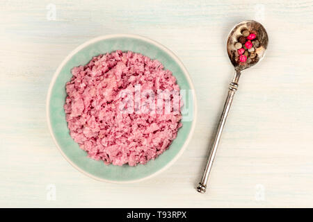 Eine Schüssel mit rosa Himalaya Salz Pfeffer mischen, mit einem Schuß von der Oberseite auf weißem Holz- Hintergrund Stockfoto