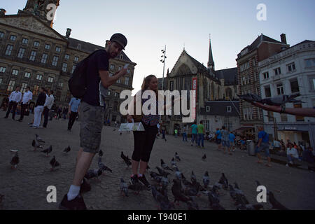 Massen von Touristen Füttern der Tauben in der Mitte des Dam Platzes im Stadtzentrum von Amsterdam. Stockfoto