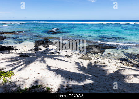 Tropische Landschaft Blick auf Strand in Polynesien mit perfekter weißer Sand, Palmen, Palmen Schatten im Vordergrund, Ozean mit türkisfarbenem Wasser und tief b Stockfoto