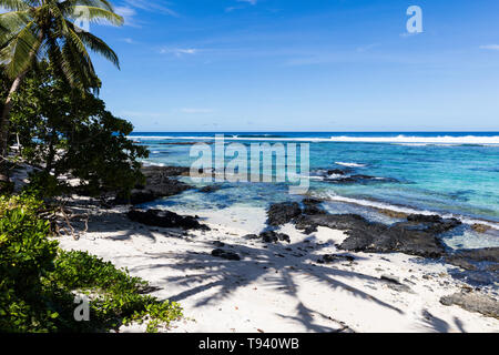 Tropische Landschaft Blick auf Strand in Polynesien mit perfekter weißer Sand, Palmen, Palmen Schatten im Vordergrund, Ozean mit türkisfarbenem Wasser und tief b Stockfoto