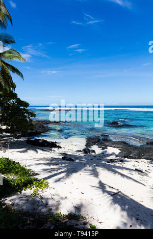 Tropische Landschaft Blick auf Strand in Polynesien mit perfekter weißer Sand, Palmen, Palmen Schatten im Vordergrund, Ozean mit türkisfarbenem Wasser und tief b Stockfoto