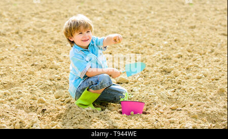 Glückliches Kind Gärtner Gärtnerei. Frühling Saison. Tag der Erde. neues Leben. Sommer Bauernhof. kleines Kind Einpflanzen einer Blume. Mensch und Natur. Organic Farm. planet Schutz. Die Arbeit mit Vergnügen. Stockfoto