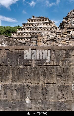 Geschnitzte relief Tafeln an den Wänden des Südens Ballcourt mit der Pyramide der Nischen hinter an der Präkolumbianischen archäologischen Komplex von El Tajin in Tajin, Veracruz, Mexiko. El Tajín von 600 bis 1200 CE und während dieser Zeit zahlreiche Tempel, Paläste, ballcourts blühte, und die Pyramiden wurden von der Totonac Menschen erbaut und ist eines der größten und wichtigsten Städte der klassischen Ära der Mesoamerika. Stockfoto