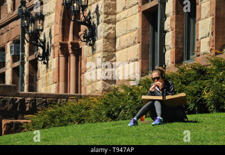 Boston, MA/USA, 17. April 2019: Frau Essen eine Pizza zum Mittagessen auf dem Gras Stockfoto