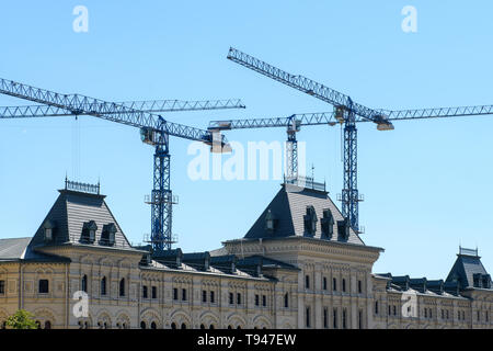 In mehreren Arbeitsgruppen Turmdrehkrane über das Dach einer gotischen Gebäude vor blauem Himmel Stockfoto