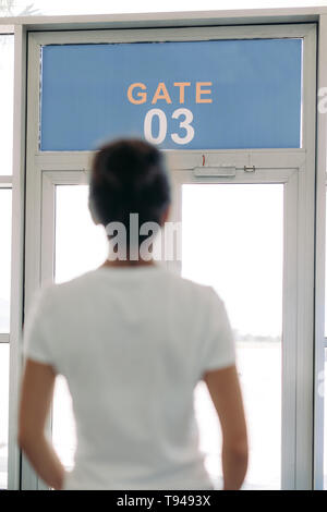 Reisende junge Frau steht vor dem Tor in einem Flughafen Stockfoto