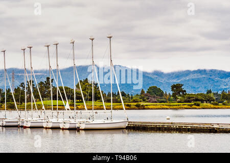 Vermietung segeln Boote aufgereiht auf einem Pier in South San Francisco Bay Area, Shoreline See und Park; Santa Cruz Mountains im Hintergrund sichtbar; Moun Stockfoto