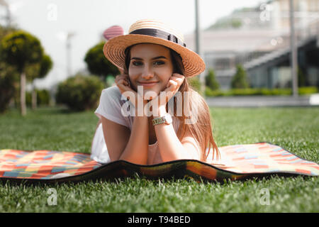 Schöne junge Mädchen ist die Verlegung an der Decke im Park und lächelnd. Stockfoto