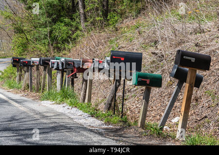 US-Mailboxen auf Holz- Beiträge in einer Reihe entlang einer ländlichen Fahrbahn Stockfoto