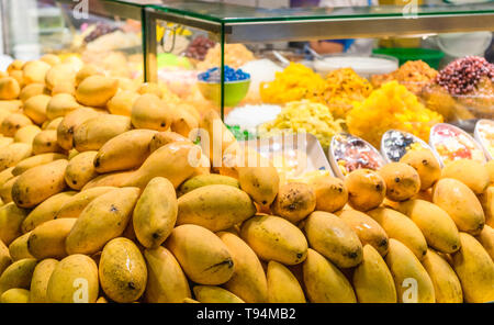 Geschlossen bis ein Bündel von Mangos mit farbenfrohen thailändischen süßen Nachtisch im Hintergrund auf. Reife mango an Street Food Shop für thailändische Dessert Mango ein Stockfoto