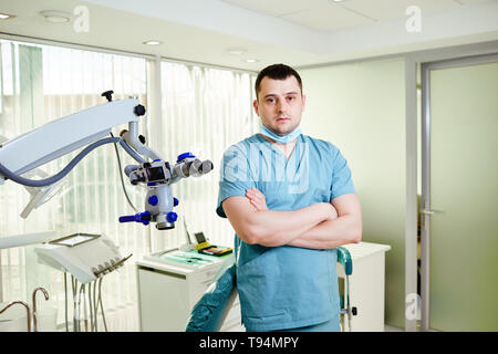 Ein männlicher Zahnarzt steht mit einem Mikroskop Stockfoto