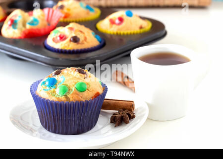 Hausgemachte lemon Muffins mit bunten Pralinenherstellung in Papier und Tasse Kaffee. Weißer Hintergrund. Selektiver Fokus Stockfoto