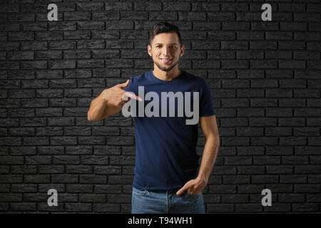 Junger Mann in stilvoll-t-shirt gegen die dunkle Mauer Stockfoto