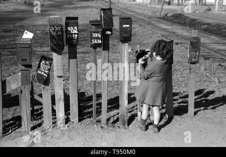 Mit dem Titel: "Kleines Mädchen, die e-mail aus, Vorort von Oklahoma City, Oklahoma." Vor der Einführung des ländlichen Kostenlose Lieferung (RFD) von der Post im Jahr 1896, viele ländliche Bewohner hatten keinen Zugang zu E-Mail, es sei denn Sie sie in einem Postamt viele Meilen entfernt von ihren Häusern gesammelt oder angestellt, ein eigenes Unternehmen zu liefern. Aus diesem Grund, Mailboxen nicht beliebt im ländlichen Amerika geworden, bis Bordsteinkante RFD Zustellung durch die Post war ein etablierter Service. Stockfoto