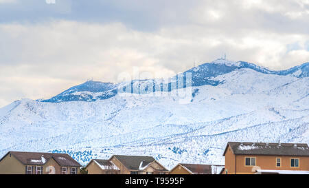 Klar Panorama der Stadt, erbaut auf einem Berg bedeckt mit frischem Schnee gegen Wolke erfüllte Himmel Stockfoto