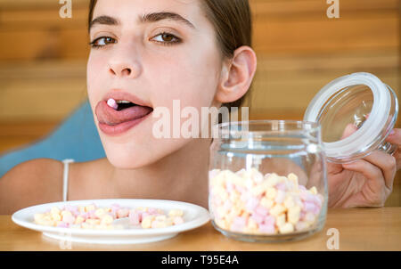 Diebstahl ein wenig Süße. Pretty Woman halten Marshmallows auf der Zunge. Lustige Frau genießen essen Marshmallows. Candy Girl mit süß Süßwaren Stockfoto