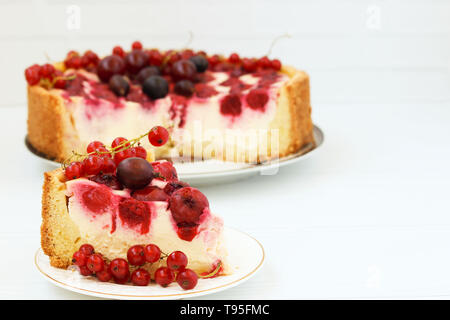 Kuchen mit Beeren auf einem Schild auf einem weißen Hintergrund, Stück Kuchen im Vordergrund befindet, Freier Platz für die Beschriftung Stockfoto