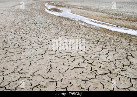 Risse in den Kanal des ausgetrockneten Fluss mit Eis im Herbst fallen. Abstraktion, Hintergrund, Textur, Ökologie. Stockfoto