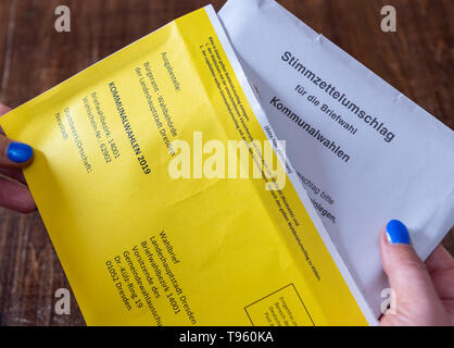 17. Mai 2019, Sachsen, Dresden: Illustration - eine Frau schiebt einen Umschlag in ein Kuvert für die Briefwahl für die Kommunalwahlen in Sachsen. Foto: Robert Michael/dpa-Zentralbild/dpa Stockfoto