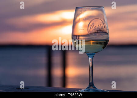 Farbenfroher Sonnenuntergang mit Glas Wein am Wasser Dock an Caps auf dem Wasser, ein lokales Seafood Restaurant in St. Augustine, Florida. (USA) Stockfoto