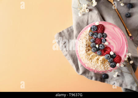 Glasschale mit rosa Joghurt und frischen Früchten auf farbigen Hintergrund Stockfoto