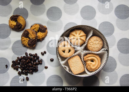 Cookies mit Zucker in einem runden Feld und drei Liegen mit Kaffeebohnen auf eine Tischdecke mit Polka Dots Stockfoto