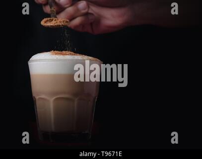 Gießen Zimt auf einem gut gemachten Schaum Kaffee mit Platz für Text Stockfoto