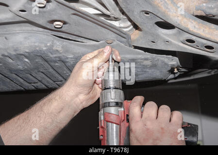 Mechaniker bei der Arbeit. Eine Schraube mit dem Akkuschrauber befestigen Stockfoto