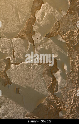 Gelbe pebbledash Wand, schmutzig und alt Risse beschädigt Pflasterwand Hintergrund durch die Mittagssonne leuchten geknackt Stockfoto