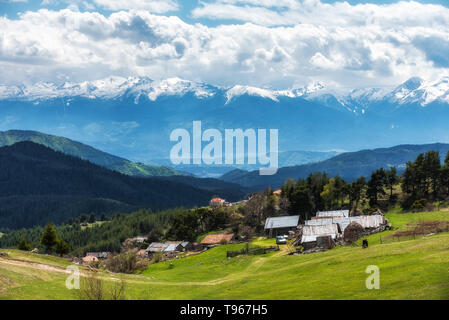 Bewölkt Frühling über höchste Dorf am Balkan und in Bulgarien - Ortsevo in Rhodopen Gebirge. Hohe verschneite Pirin Gebirge im Hintergrund. Stockfoto