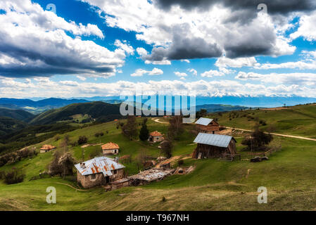 Bewölkt Frühling über höchste Dorf am Balkan und in Bulgarien - Ortsevo in Rhodopen Gebirge. Hohe verschneite Pirin Gebirge im Hintergrund. Stockfoto