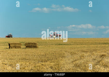 Zwei Traktoren der Fahrt über die Stoppeln Feld, Horizon und blauer Himmel Stockfoto