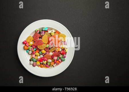 Blick von oben auf die leckere bunte Karamell Bonbons und Citrus Gelee in Weiß auf schwarzem Hintergrund mit Kopie Raum Stockfoto