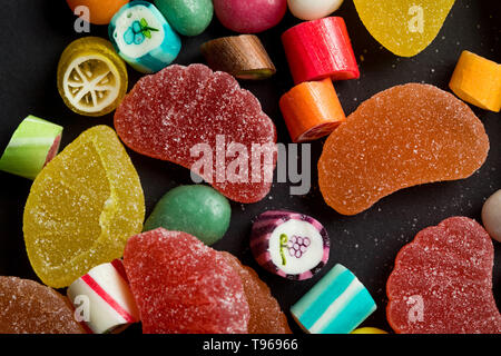 Nahaufnahme, Ansicht von Karamell bunte Süßigkeiten und zuckerhaltige Fruchtgelees auf schwarzem Hintergrund Stockfoto