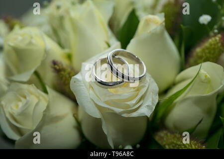 Eheringe auf natürlichem Rosenstrauß Stockfoto