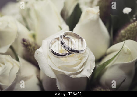 Eheringe auf natürlichem Rosenstrauß Stockfoto
