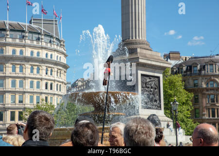 Reiseführer führenden Rentner auf eine Wanderung rund um den Trafalgar Square mit einem langen Stock und eine kleine Abbildung an einem warmen sonnigen Tag im Frühjahr angebracht. Stockfoto