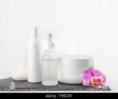 Anderes Material, Form und Größe Kosmetik Creme, Öl behälter auf weißem Hintergrund stehen auf schwarzen Stein Base, Pink Orchid Blossom. Stockfoto